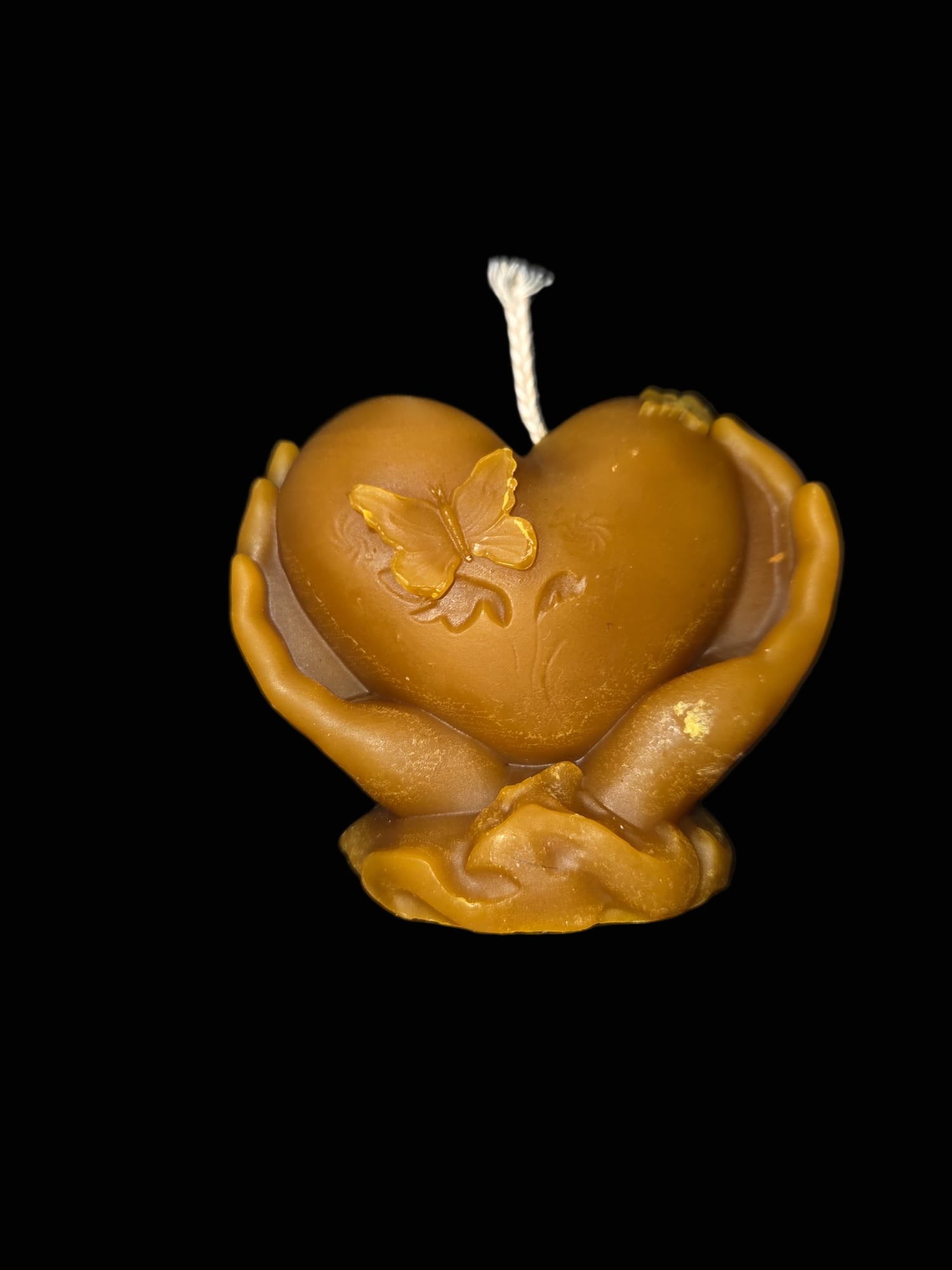 Figura de corazón entre manos de cera natural de abejas
